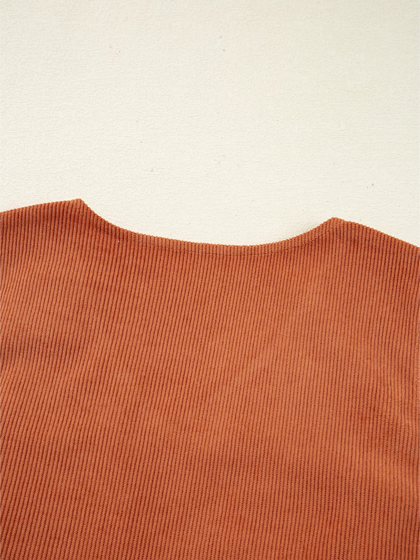 Close-up of the back neckline of a rust orange corduroy mini dress showing smooth seams and ribbed texture – minimalist styling for everyday wear and western-inspired fashion.