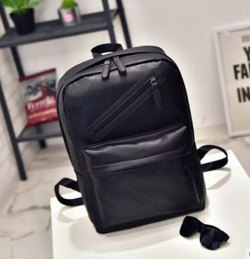 Black backpack on a white surface with a blurred background