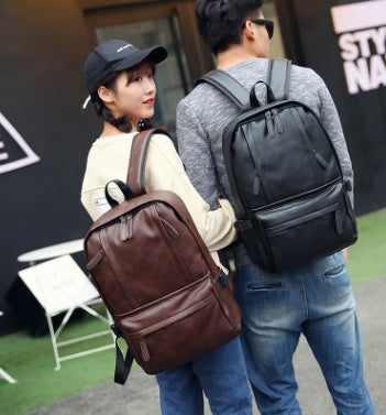 Two people with backpacks, one brown and one black, standing outdoors.