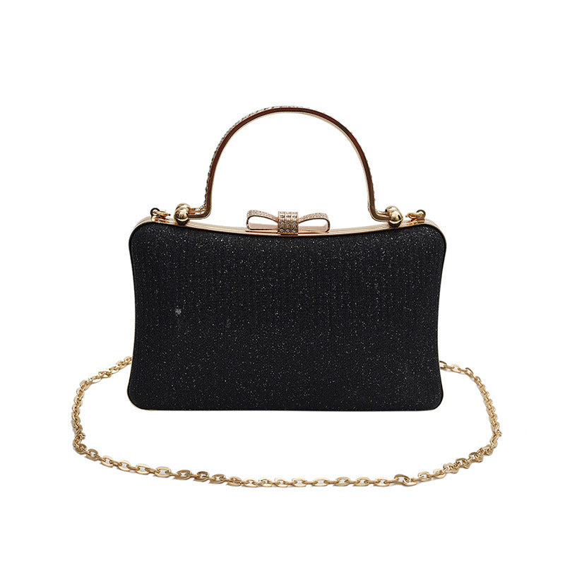 Black handbag with gold chain and handle on a white background