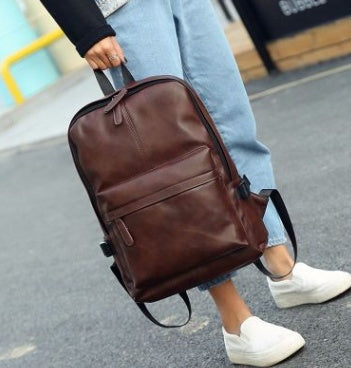 Brown backpack being carried by a person on a street.