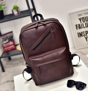Brown leather backpack on a white surface with a blurred background