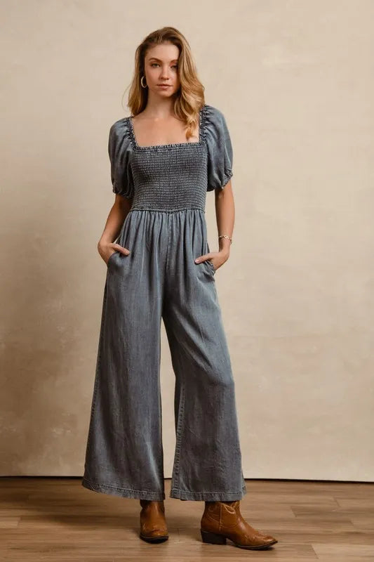 Detailed shot of braided brown boho belt over the elastic waistband of a washed denim wide-leg jumpsuit