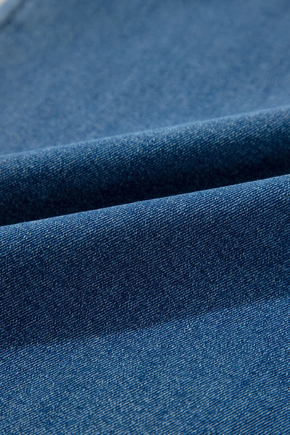Close-up view of folded blue denim fabric, showcasing its texture and weave pattern