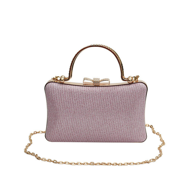 Pink handbag with gold chain and handle on a white background