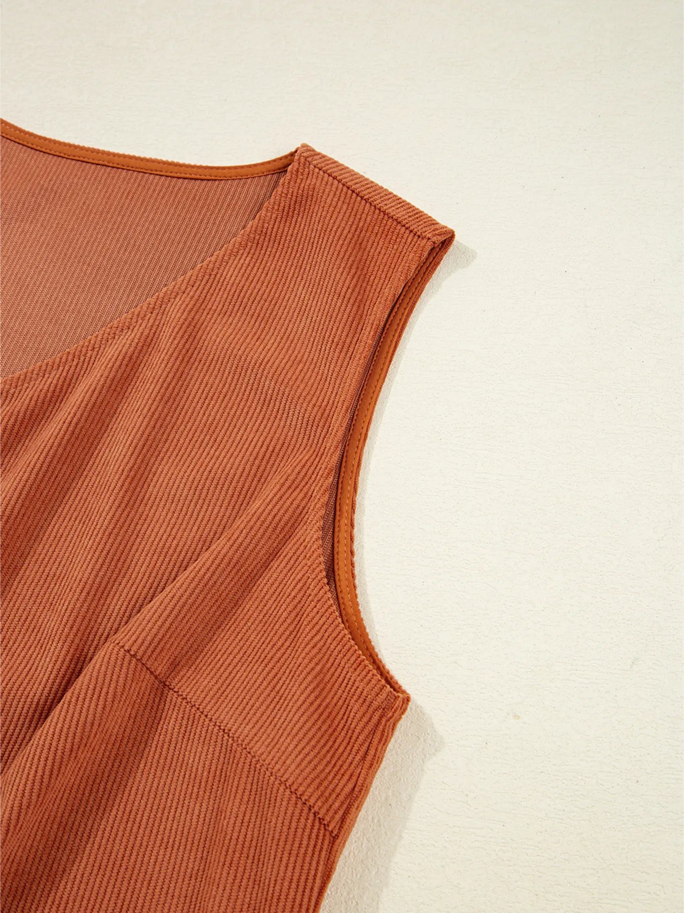 Close-up of intricate white floral embroidery on the front pocket of a rust-colored corduroy mini dress – showcasing artisan-inspired detailing perfect for boho-chic women's fashion