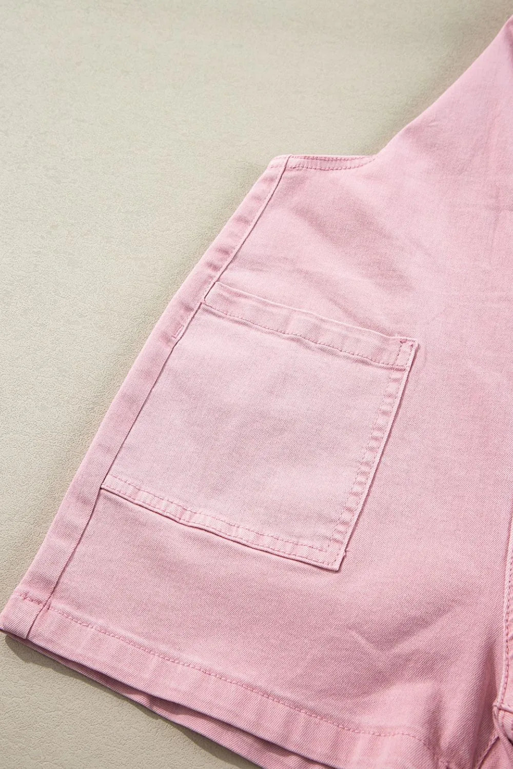 Light pink denim shorts with a pocket, laid flat.