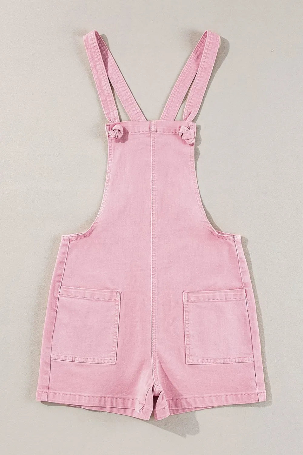 Pink denim overall shorts on a light gray background