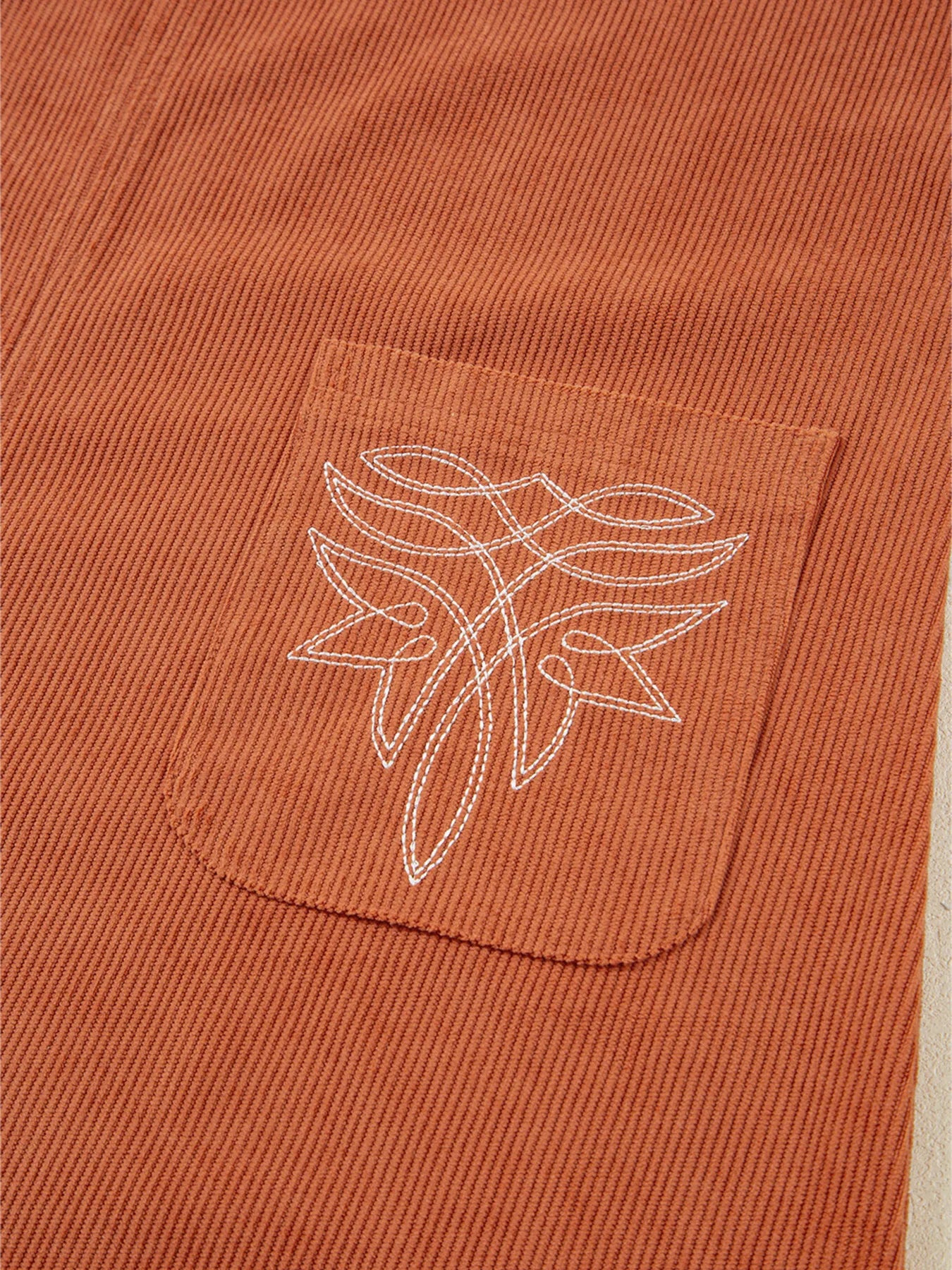 Detailed close-up of armhole and shoulder seam stitching on a rust orange corduroy mini dress – highlighting premium tailoring and comfortable fit for stylish women's fall outfits.