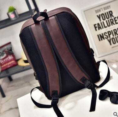Black and brown backpack on a white surface with a blurred background