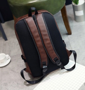 Brown and black backpack on a chair with a blurred background
