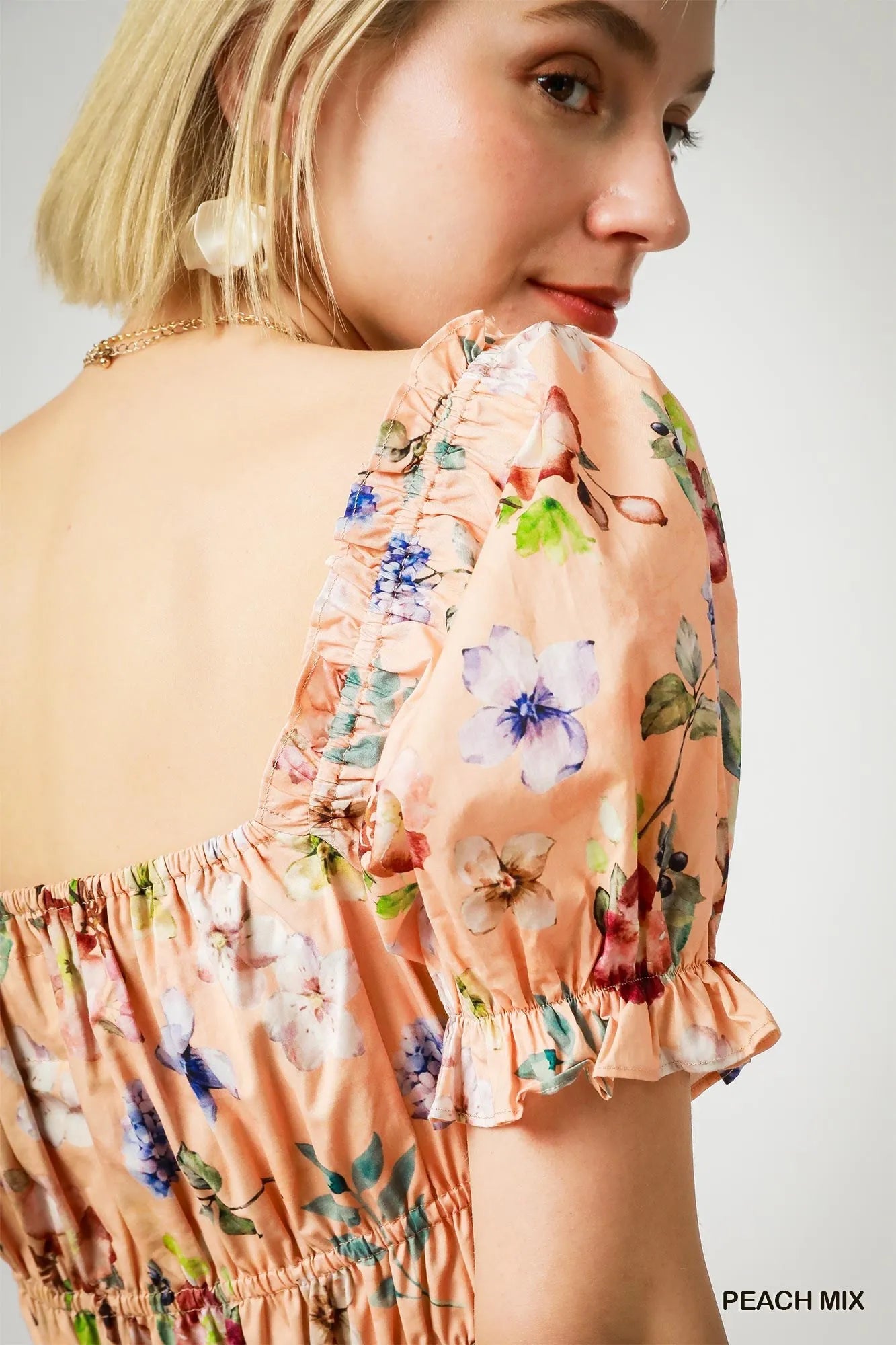 Close-up of puff sleeve detailing and floral print on peach mini dress – high-quality fabric and elegant floral accents for women.