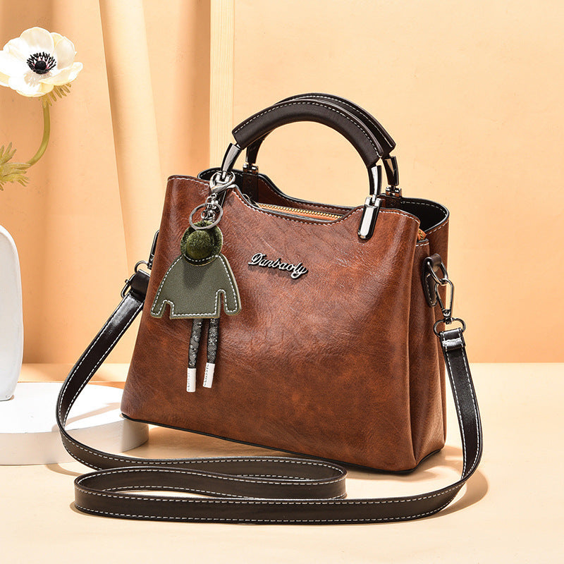 Brown handbag with decorative charm on a beige background