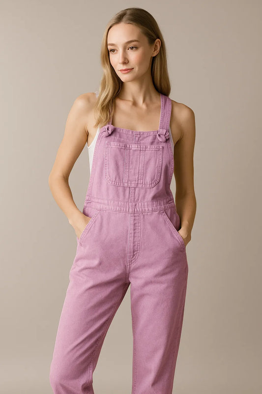 Woman wearing pastel pink denim overalls with front pockets, standing against a neutral background